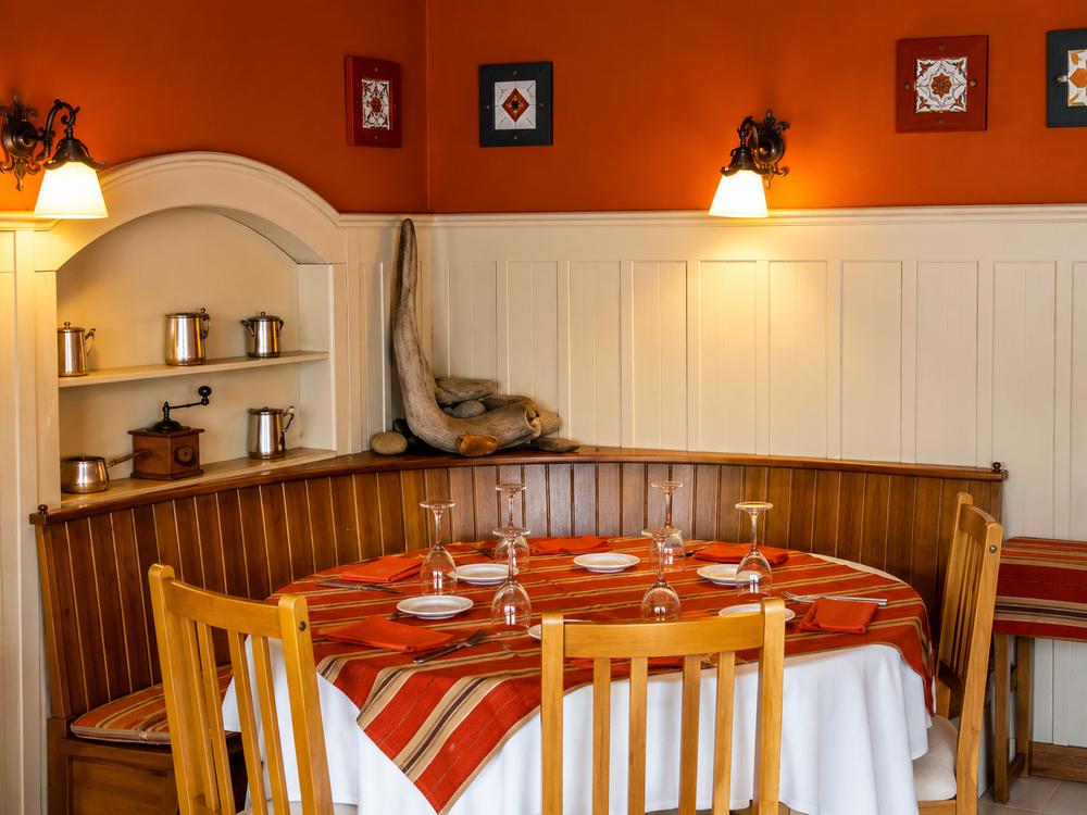 Salón comedor de La Casita, paneles de madera y mesas preparadas para la cena
