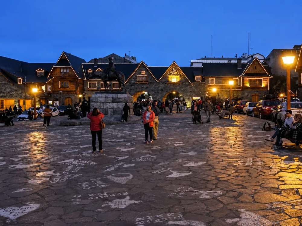 Edificios de piedra y madera del Centro Cívico iluminados al atardecer, a dos cuadras