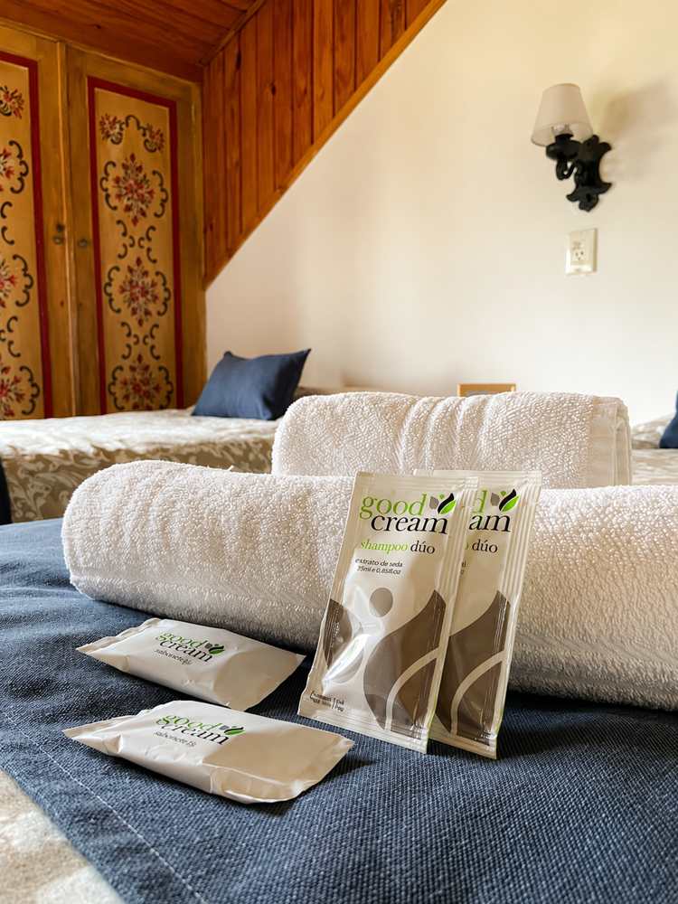 Detalle de la habitación con toallas enrolladas y amenities sobre la cama